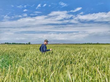 Man standing amidst plants against blue sky