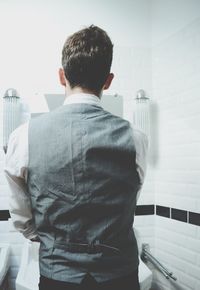 Rear view of man in bathroom