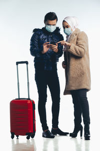 Man and woman standing on smart phone against white background