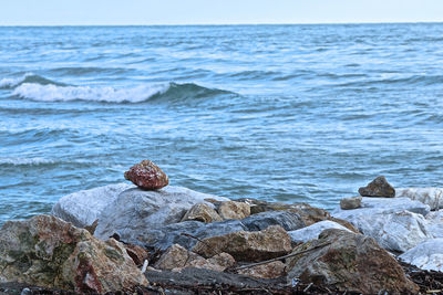 Stone poised on the rocks facing the sea.