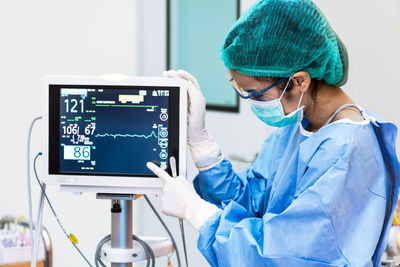 Surgeon checking monitoring equipment in operating room at hospital