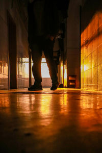 Low section of man standing on illuminated walkway