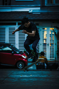 Man skateboarding on footpath against building