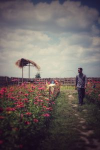 Rear view of man on flowering plants against sky