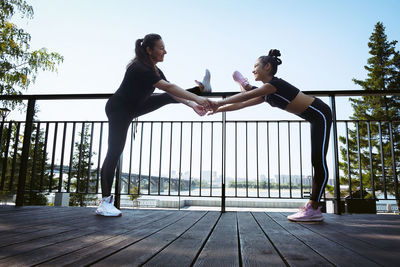 Mom and daughter in sportswear on a sunny summer day on the embankment in the park 