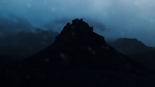 Low angle view of silhouette mountain against cloudy sky