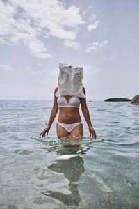 Young woman in bikini on sea against sky
