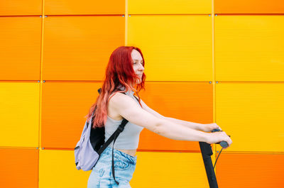 Young bright woman smiles and rides an electric scooter in the summer in city