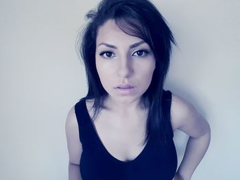 Portrait of young woman standing against wall