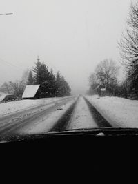 Road amidst trees against clear sky during winter