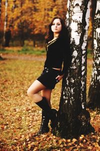 Portrait of smiling young woman standing in forest during autumn