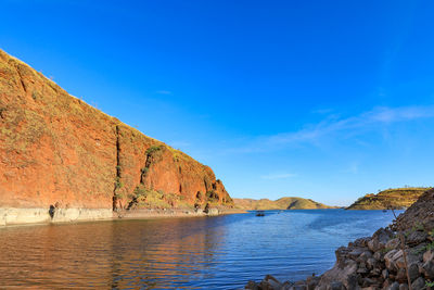 Scenic view of sea and rocks against blue sky