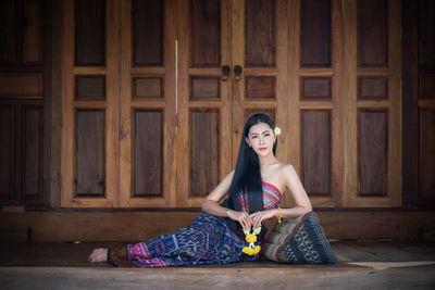 Young woman relaxing against closed wooden door