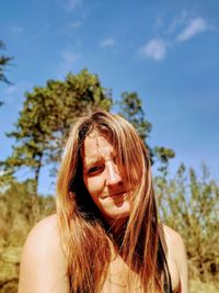 Portrait of woman with brown hair standing against sky