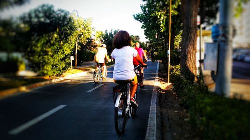 Rear view of women riding bicycle on road