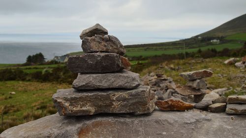 Stack of stones on rock against sky