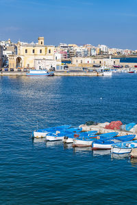 Sailboats moored on sea against buildings in city