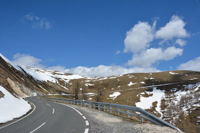 Road amidst snowcapped mountains against sky