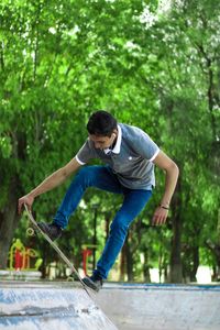 Full length of young man jumping against trees