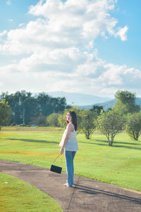 Side view of woman standing on field against sky