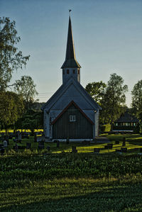 Church on field by building against sky