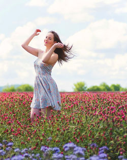 Woman with arms raised on field against sky