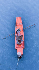 High angle view of fisher man holding rope tied to boat