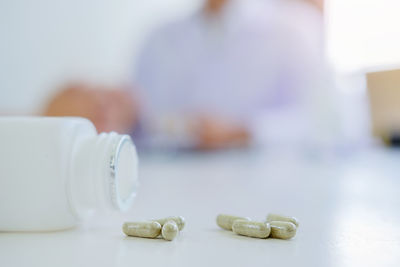 Close-up of medicines spilling from bottle on table