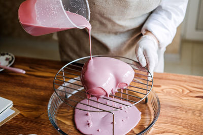 Mousse heart shape pink cake in hand of asian arabic woman pastry chef. mirror glaze cake. process