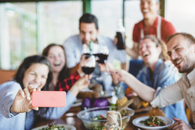 Group of happy friends taking selfie at restaurant