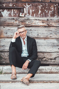 Portrait of businessman sitting against wooden wall