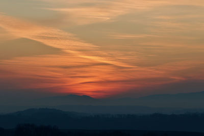 Scenic view of silhouette mountains against romantic sky at sunset