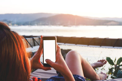 Woman using mobile phone while sitting on lounge chair