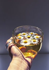 Close-up of hand holding glass of flower