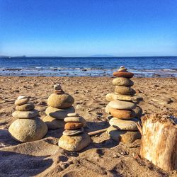 Stack of rocks on beach against clear blue sky