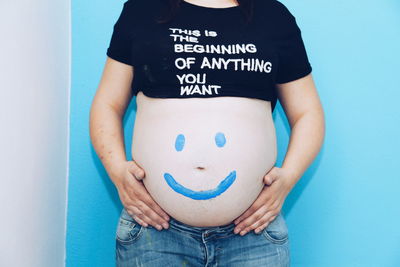 Midsection of woman wearing mask against blue background