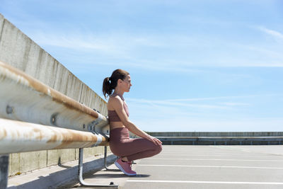 Fit sporty woman sitting, resting after working out outside