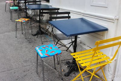 High angle view of empty chairs and tables at sidewalk cafe