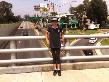 Girl standing against railing in city