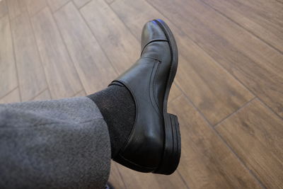 Low section of man wearing black leather shoe