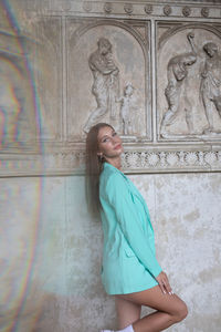 Young woman standing against wall