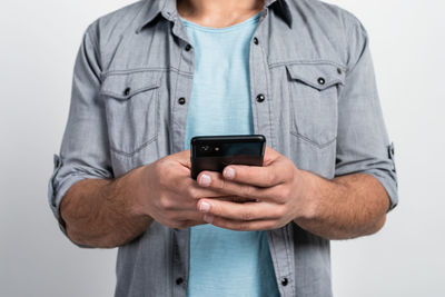 Midsection of man using smart phone against white background