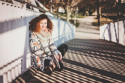 Portrait of smiling woman sitting on footbridge