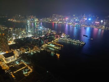 High angle view of illuminated city by sea against sky