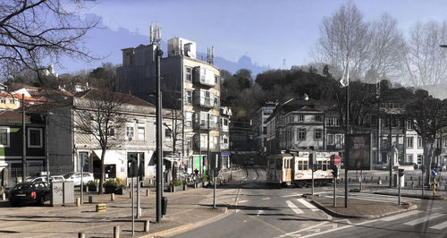 Road by buildings in city against sky