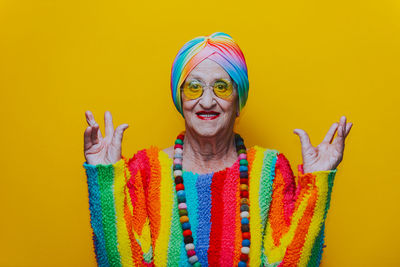 Portrait of senior woman gesturing against yellow background