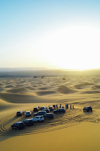 People watch the sunset in the moroccan desert from their 4x4 cars