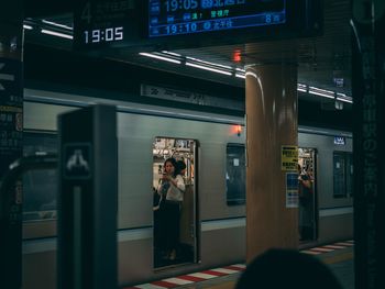 Reflection of woman on illuminated mirror at bus