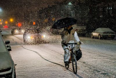 Woman with umbrella on wet street at night