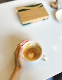 Cropped hand of woman holding coffee on table